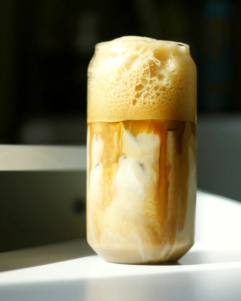 Cold brew under a thick cap of sweet cream foam, in sunlight.