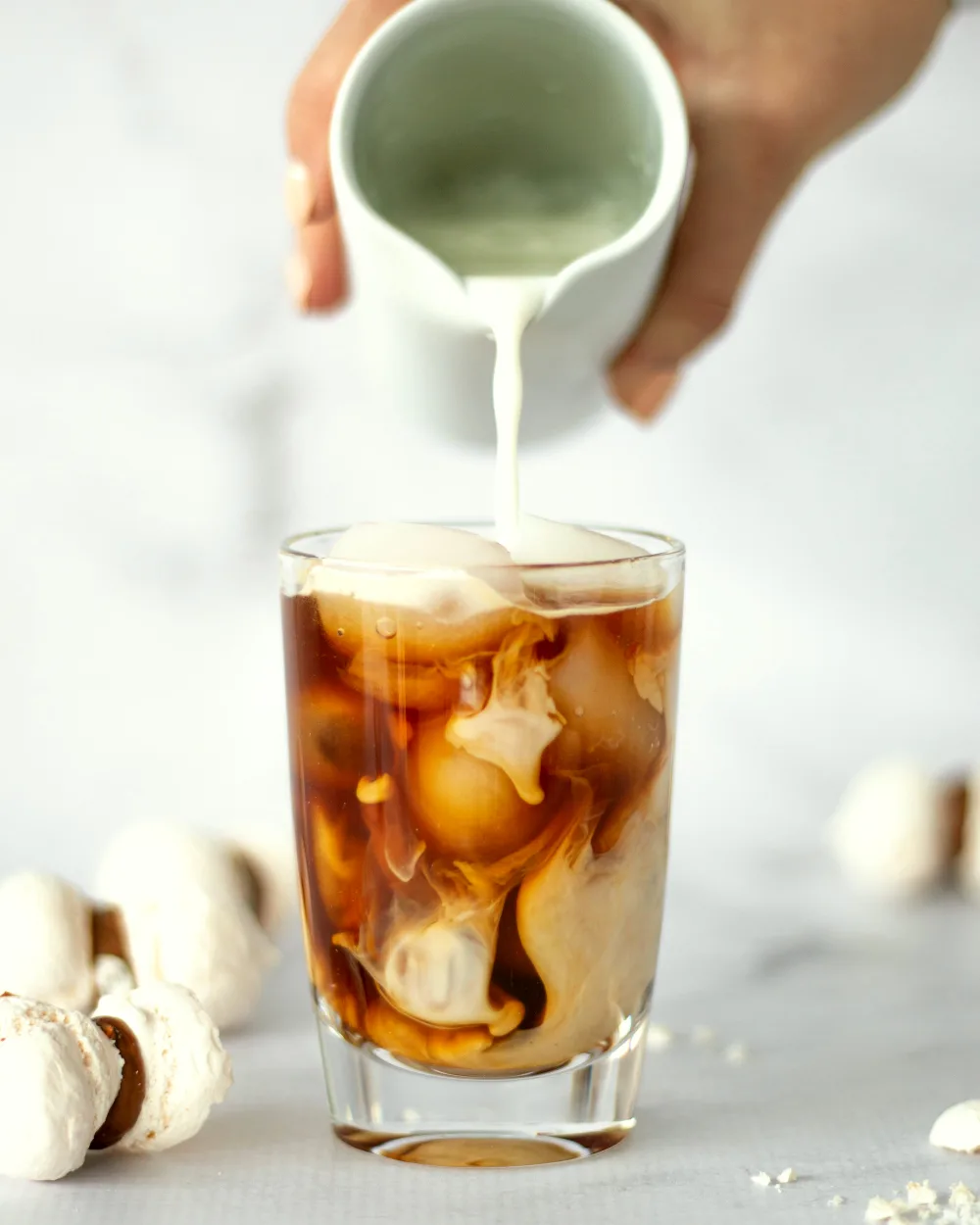Cold milk poured into a glass of iced coffee.